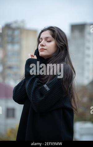 Young brunette girl in black sweater standing on open air Stock Photo