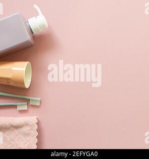 Spa bathroom products. Shampoo bottle, cup, toothbrush, towel on pink background. top view, copy space Stock Photo