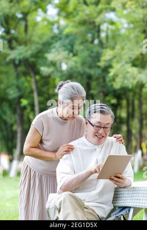Happy elderly couples use tablet computers in the park Stock Photo