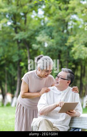 Happy elderly couples use tablet computers in the park Stock Photo