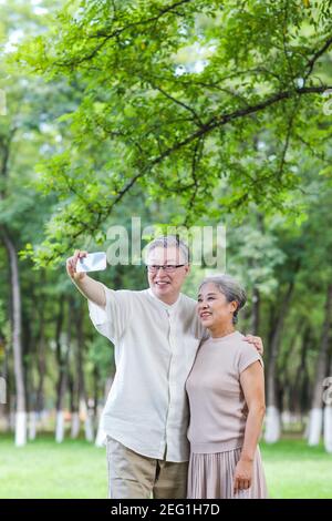 Happy old couple take selfie with mobile phone in the park Stock Photo