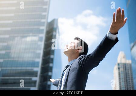 Happy businessman raising his arms, open palms, with face looking up  - empower, success and freedom concepts Stock Photo