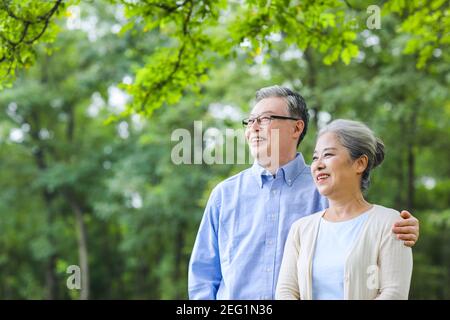 Happy old couple looking at the scenery in the park holding the shoulder Stock Photo