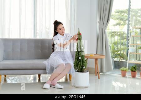 She hangs toys on the Christmas tree. Stock Photo