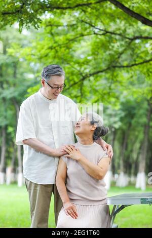 Happy old couple sitting on chairs in the park Stock Photo