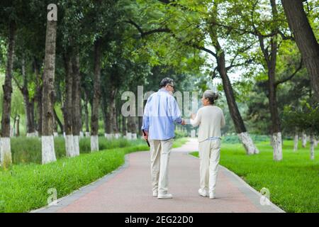 Happy old couple walking in the park Rear view Stock Photo