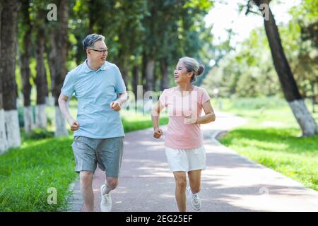 Old couple jogging in outdoor park smiling Stock Photo