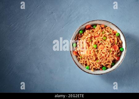 Instant noodles with green peas and carrot, shot from the top with a place for text Stock Photo
