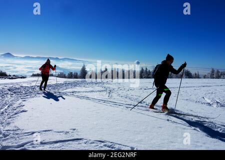 Silhouettes of a pair of skiers enjoying a nice sunny day in a snowy landscape Stock Photo