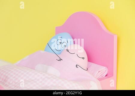 Lovely couple eggs sleeping in an embrace in bed. holding hands.Easter holiday concept with cute eggs with funny faces. Different emotions and Stock Photo