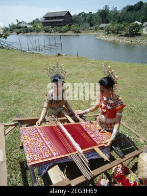 Asia,Malaysia, Sarawak, Sarawak Cultural Village pretty Iban girls wearing  Traditional Costume doing Traditional Weaving Stock Photo