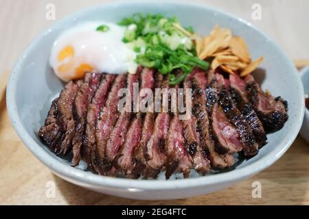 Close up Sliced medium rare Wagyu beef served on rice and topped with poached egg Stock Photo