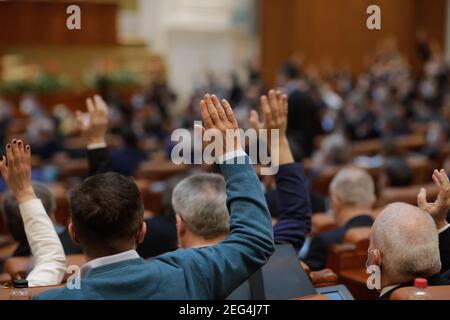 Bucharest, Romania - February 17, 2021: Shallow depth of field (selective focus) with details of Romanian MPs voting by raising their hands. Stock Photo
