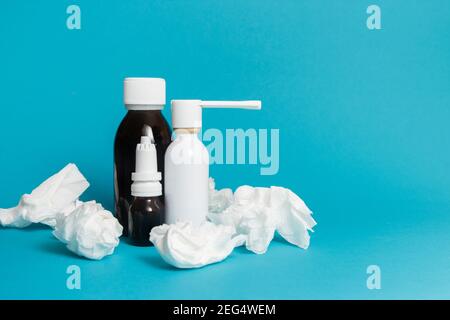 Treatment of colds and flu. Various medicines, sprays from a stuffy nose and a pain in a throat with napkin on a blue background. Copy space. Stock Photo