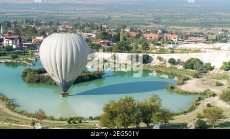 Denizli, Turkey - October 2019: Hot air balloon touching the pool near Pamukkale travertine Stock Photo