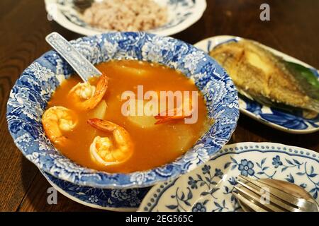 Shrimp sour curry soup served with deep fried Gourami (Gouramy) fish and brown rice Stock Photo