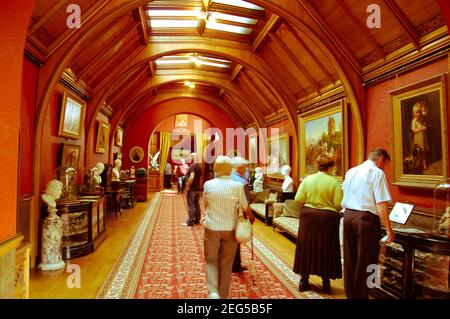 Picture gallery in Cragside Northumberland UK painting paintings arch arched people visit visiting artwork art old Victorian style tourist tourists Stock Photo
