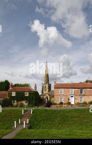 Historic St. Edith's Church (tall spire), village green beck & quaint cottages under blue sky - Bishop Wilton, East Riding of Yorkshire, England, UK. Stock Photo