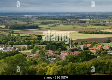 Scenic view of Bishop Wilton village (houses & church) & open flat low-lying Vale of York farmland fields - Yorkshire Wolds, East Riding, England UK. Stock Photo