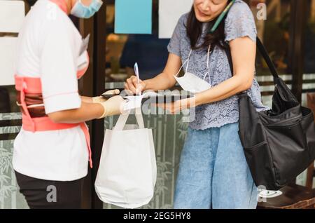 Woman signing slips payment credit card for take out food. Stock Photo