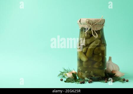 Jar of pickled cucumbers and ingredients on mint background Stock Photo