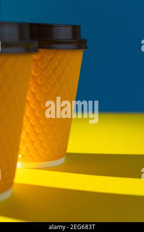Yellow ribbed paper cup with plastic lid for takeaway beverage in fast food restaurants. A cup of coffee, cocoa, tea from a street cafe. Place for you Stock Photo
