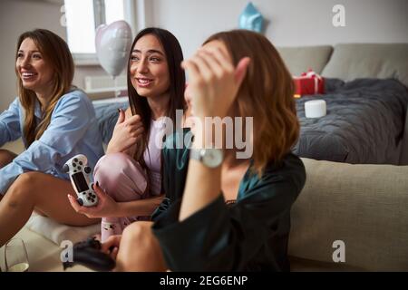 Smiling dark-haired woman playing a video game with her guests Stock Photo