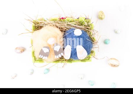 two handmade fluffy easter handmade bunnys and colorful eggs in basket with hay. Easter, holidays and celebration concept. Greeting card. Selective fo Stock Photo