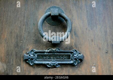 Decorative door knocker and mail slot adorn a wooden entrance in a historic building Stock Photo