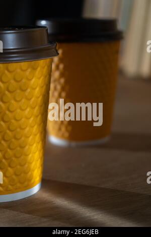 Yellow ribbed paper cup with plastic lid for takeaway beverage in fast food restaurants. A cup of coffee, cocoa, tea from a street cafe. Place for you Stock Photo