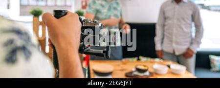 Unrecognizable camera operator recording cooking workshop. Selective focus on camera in foreground Stock Photo