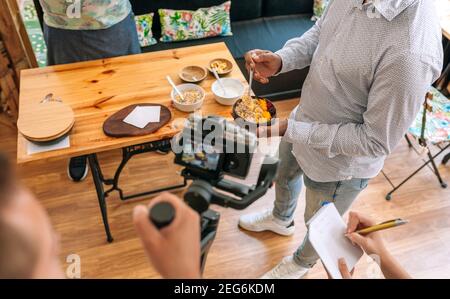 Unrecognizable camera operator recording a streaming cooking tutorial. Selective focus on breakfast bowl in background Stock Photo