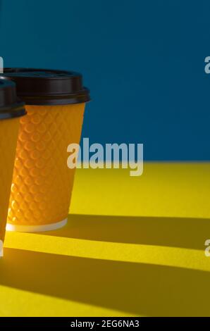 Yellow ribbed paper cup with plastic lid for takeaway beverage in fast food restaurants. A cup of coffee, cocoa, tea from a street cafe. Place for you Stock Photo
