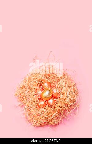 Happy easter background, colored pink and golden eggs in hay nest over bright pink color, top view with space Stock Photo