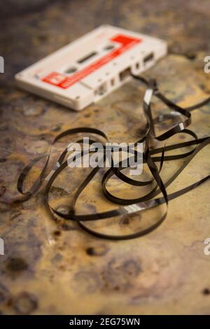 Old cassette tape with tangled tape lying on a textured surface, evoking nostalgia for vintage music Stock Photo