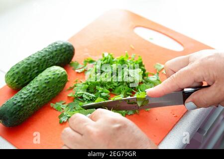 Woman hands cutting parsley on plastic board. Kitchen interier Stock Photo