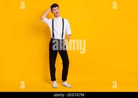 Full length body size photo unsure doubtful clueless man looking blank space touching head isolated on vivid yellow color background Stock Photo