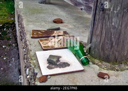 An old abandoned house and a broken glass bottle and tiles on the entrance terrace of the same. Stock Photo