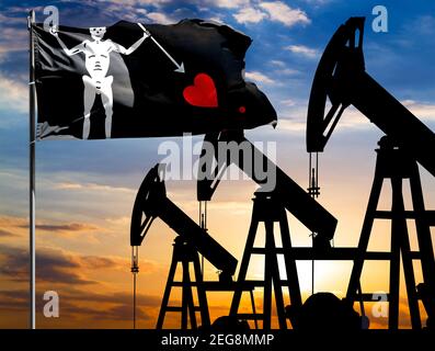 Oil rigs against the backdrop of the colorful sky and a flagpole with the flag of Blackbeard Pirate. The concept of oil production, minerals, developm Stock Photo