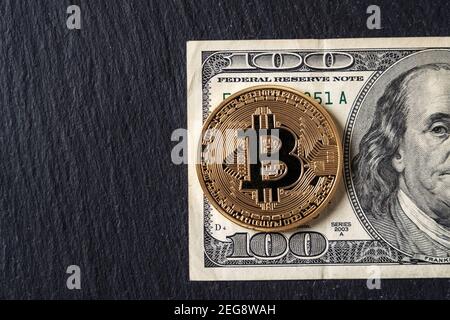 Bitcoin cryptocurrency equivalent to dollar, a banknote of one hundred units. Future virtual currency concept. On a background of marble, close-up. Stock Photo
