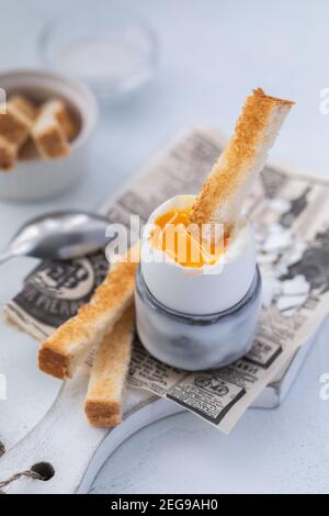 Soft-boiled egg in an eggcup breakfast with toasts and coffee on the wooden background Stock Photo