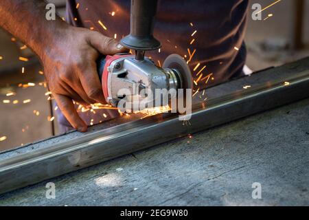 a man working cutting metal bar with a circular electric tool that shoots sparks Stock Photo