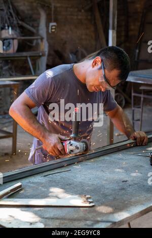 a man working cutting metal bar with a circular electric tool that shoots sparks Stock Photo