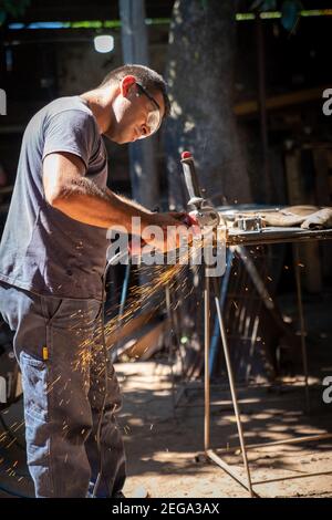 a man working cutting metal bar with a circular electric tool that shoots sparks Stock Photo