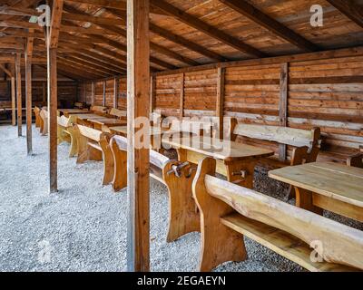 Small wooden grill hut with a lot of wooden tables and benches Stock Photo