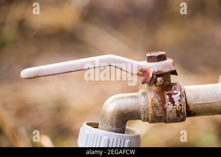 Old rusty water faucet. Abandoned device for watering plants in greenhouse. Stock Photo