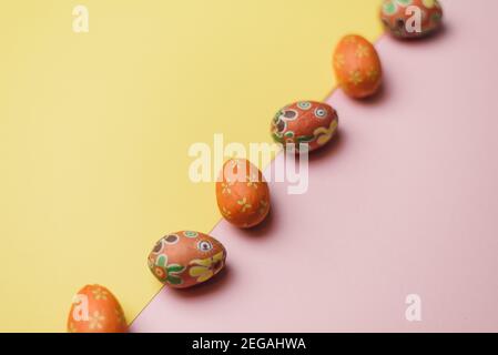 Many easter eggs on trendy pink and yellow pastel background. Eggs are decorated. Flat lay style. Easter postcard. Stock Photo