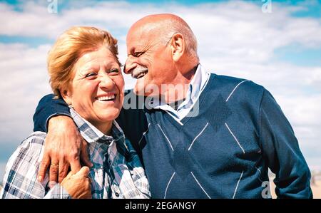 Happy senior couple in love enjoying time together - Joyful elderly lifestyle and retirement concept with man whispering on woman ear Stock Photo