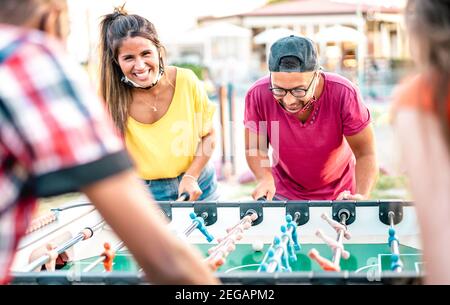 Multiracial friends play kicker table football at open space bar - New normal lifestyle concept with happy milenials having fun together Stock Photo