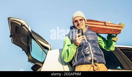 Young hipster handsome man with mobile smart phone listening music at car trip - Modern technology concept and wanderlust travel lifestyle Stock Photo